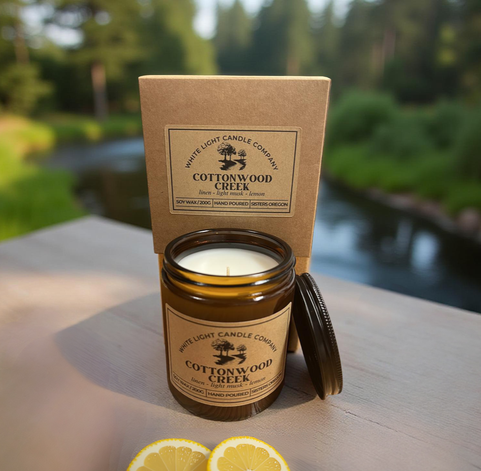 Candle jar with Cottonwood Creek branding on a wooden surface with a natural background