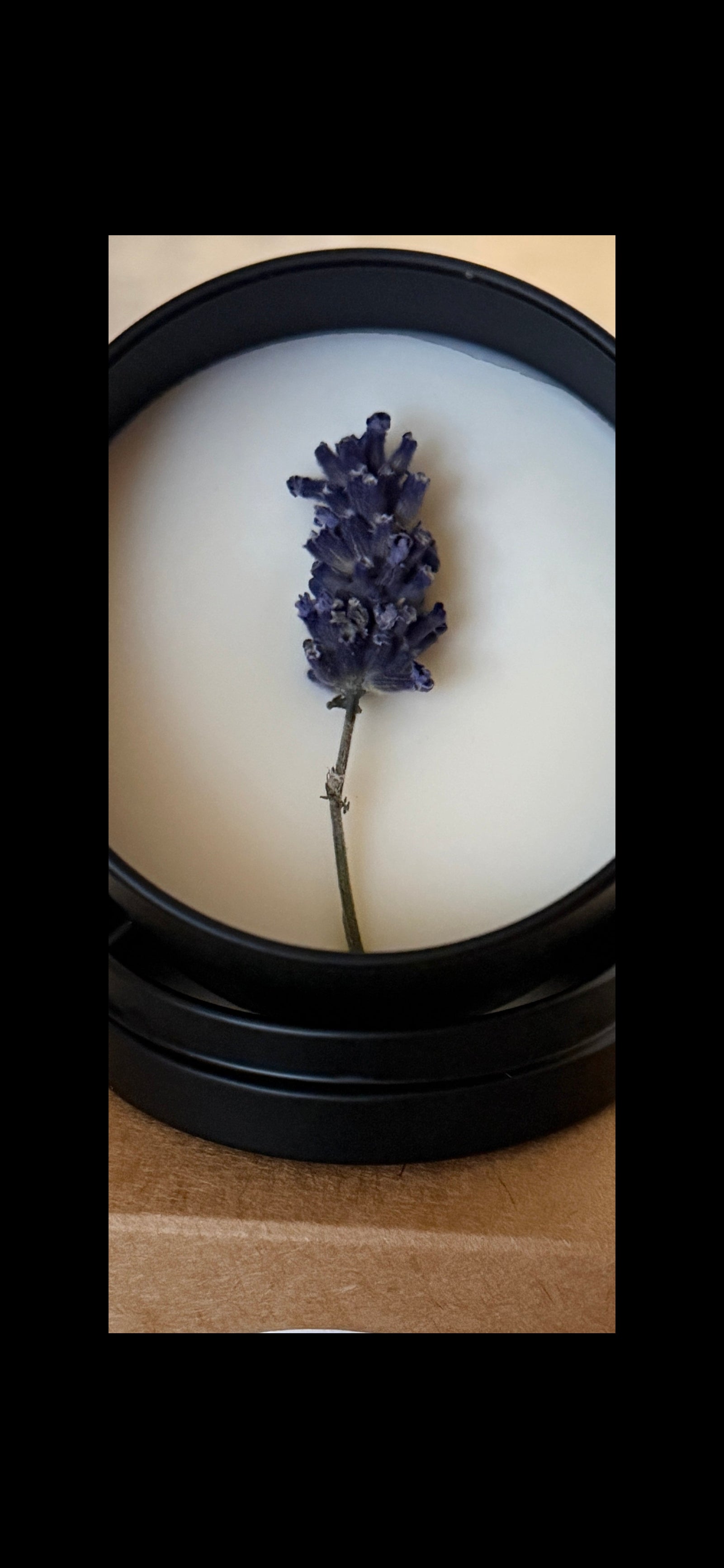 Candle with a lavender flower inside on a wooden surface